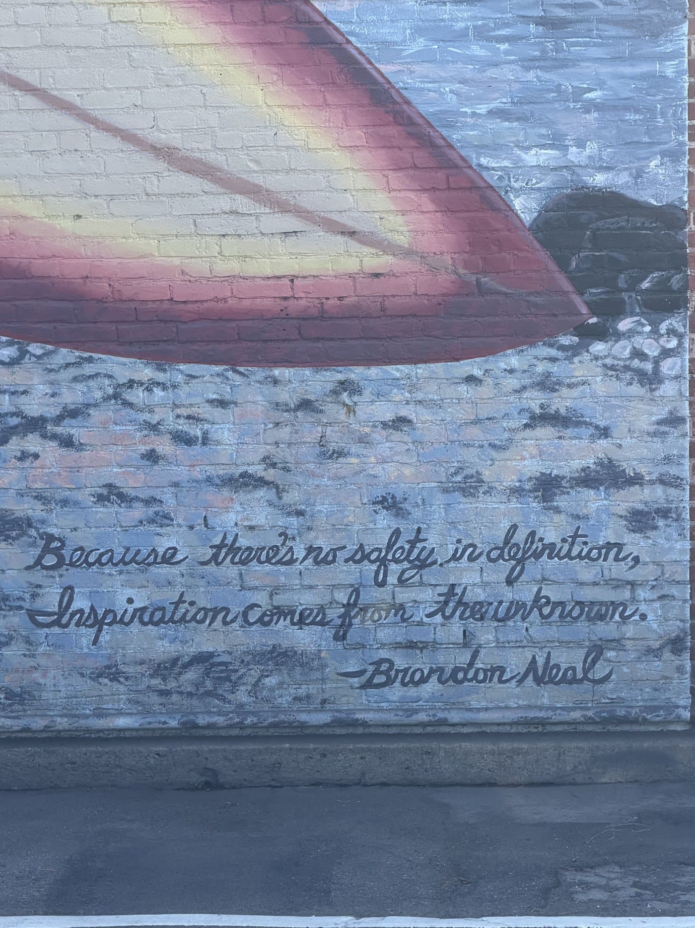 Brandon Neal's words painted in script on the mural: Because there's no safety in definition, inspiration comes from the unknown.